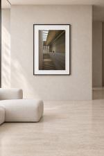 Room mockup: The photo in a black frame with white mat, on a warm beige wall above a low cream sofa.