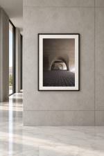 Room mockup: The photo in a black frame with white mat, on a grey stone wall beside tall windows and a marble floor.