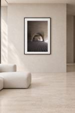 Room mockup: The photo in a black frame with white mat, on a warm beige wall above a low cream sofa.